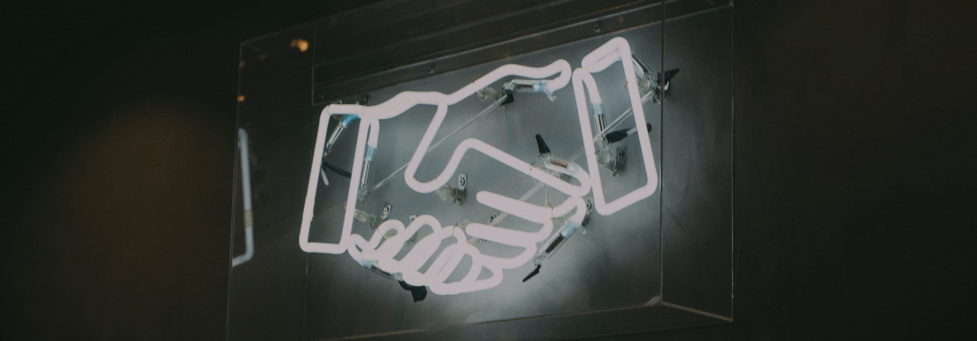 Image of neon sign of a handshake